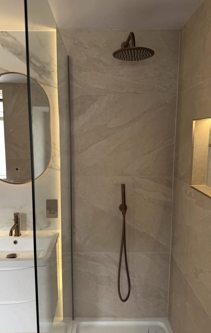 Bronze rainhead shower in a warm stone effect enclosure
