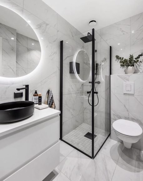 Compact marble effect en-suite with black framed corner shower and black counter basin